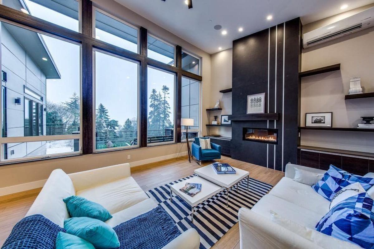 Contemporary living room with wall-to-wall windows, modern fireplace, and open layout.