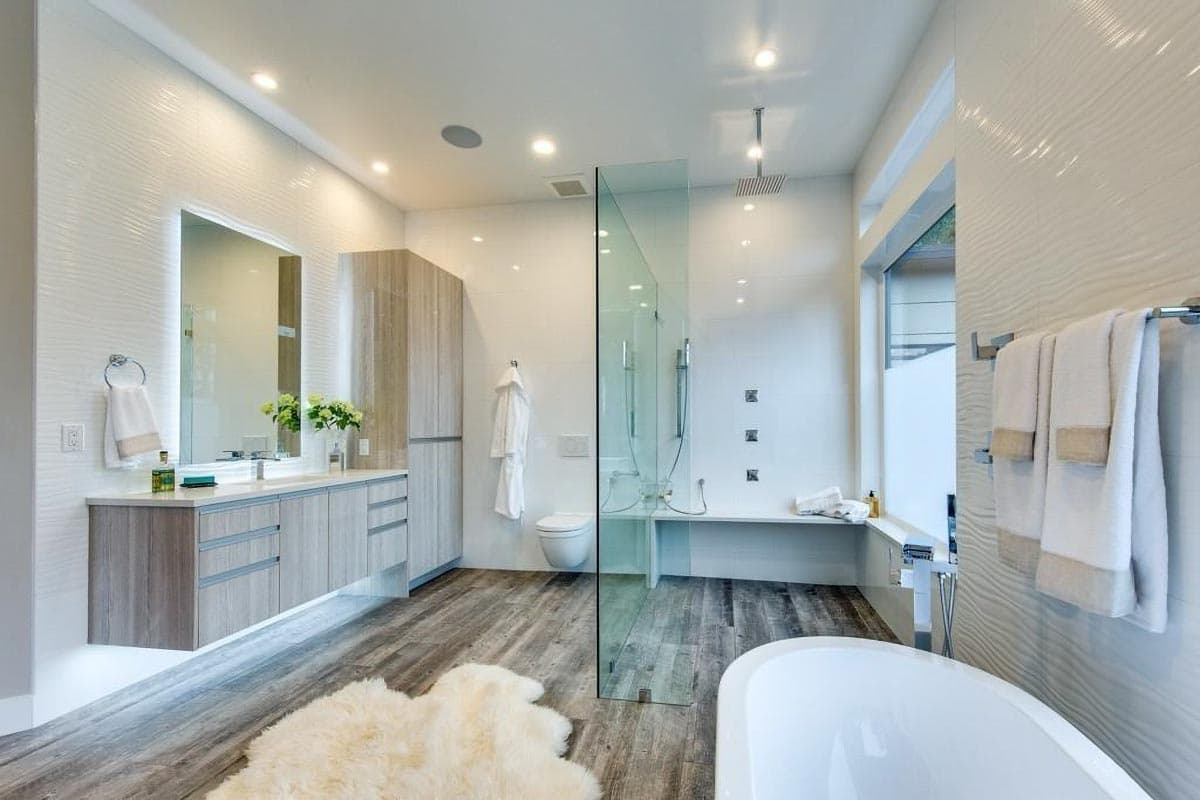 Modern bathroom with floating vanity, glass-enclosed shower, freestanding tub, and textured white wall tiles.