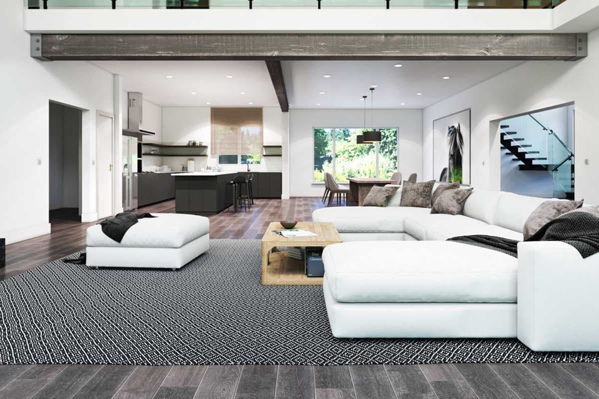 Open-concept living area with sectional sofa, island kitchen, dining area, and floating staircase with glass railings.