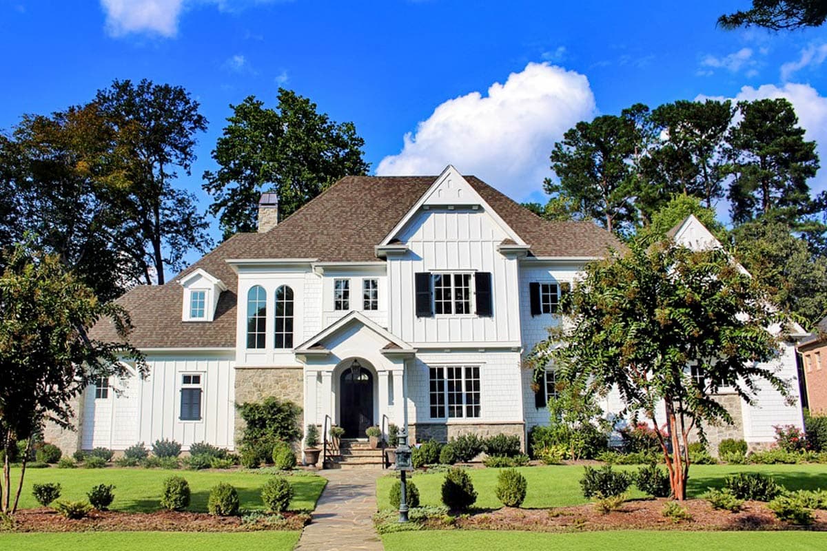 House plan exterior featuring a two-story farmhouse style home with gabled roof, dormers, stone accents, and a front porch.