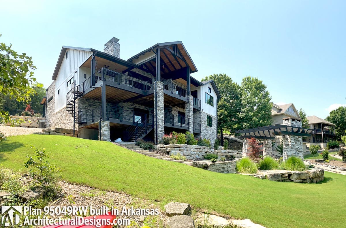 Modern Farmhouse house plan exterior with stone and vertical siding, multiple balconies, and spiral staircase.