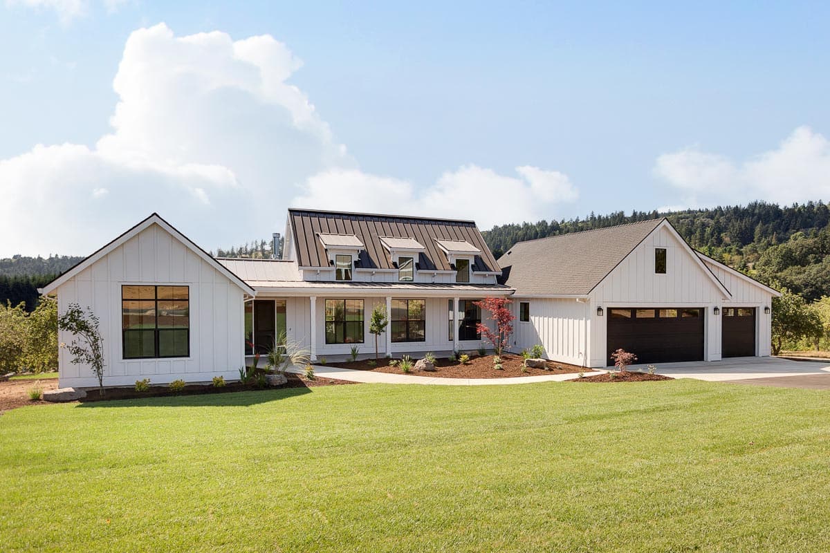 Modern Farmhouse exterior with white board-and-batten siding, standing seam metal roof, covered porch, and a three-car garage.