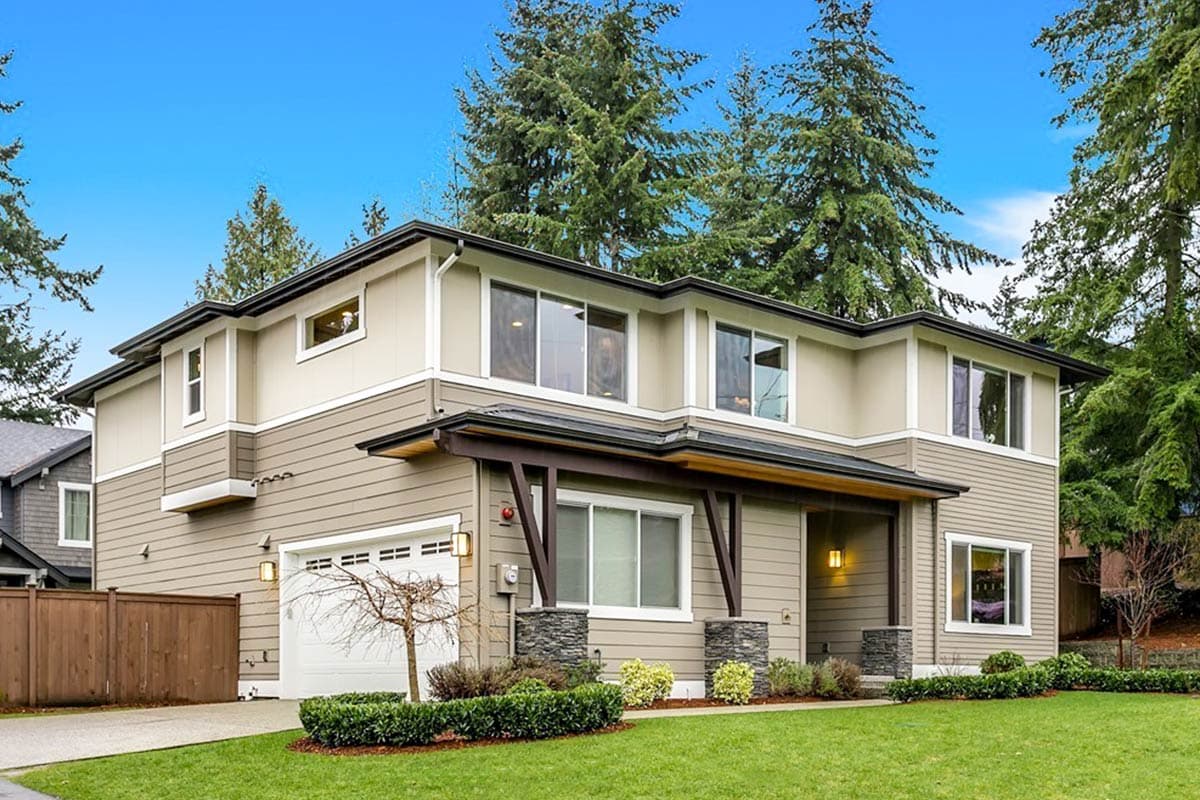 Two-story house plan exterior with beige siding, dark trim, covered entry, stone-clad pillars, and attached garage.