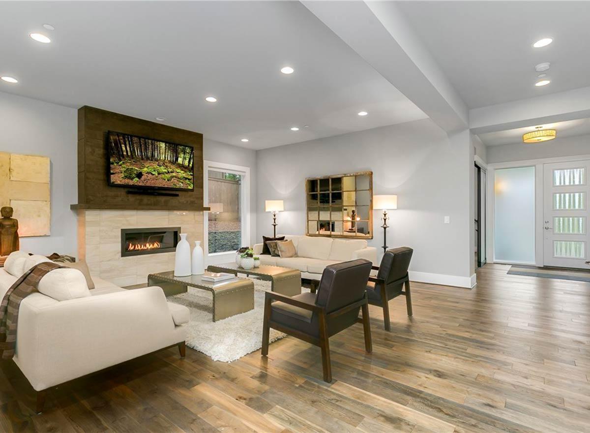 Living room with fireplace, mounted television, seating, coffee tables, and entryway with frosted glass doors.