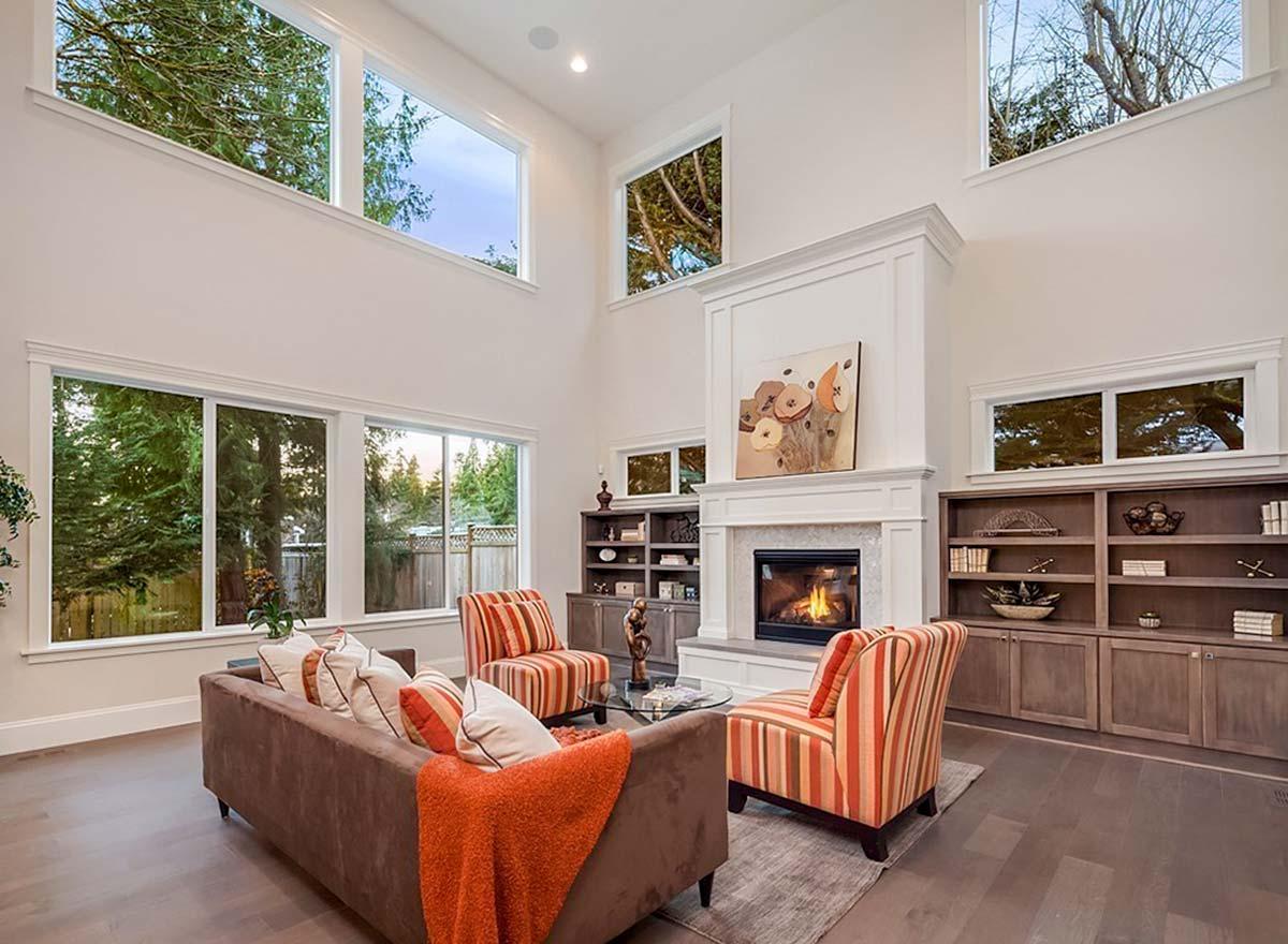 Great room with soaring ceiling, fireplace, built-in bookshelves, and large picture windows.