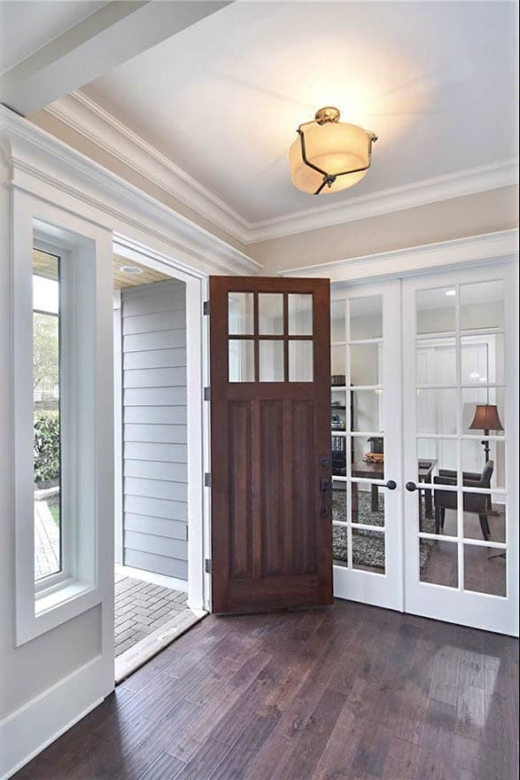 Entryway with wooden paneled door, glass French doors, and decorative ceiling light.