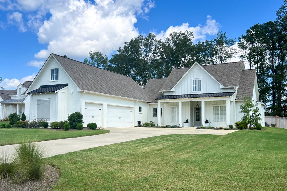 Modern Farmhouse house plan exterior with a gabled roof, covered front porch, and attached garage. Two stories with white siding and black accents.