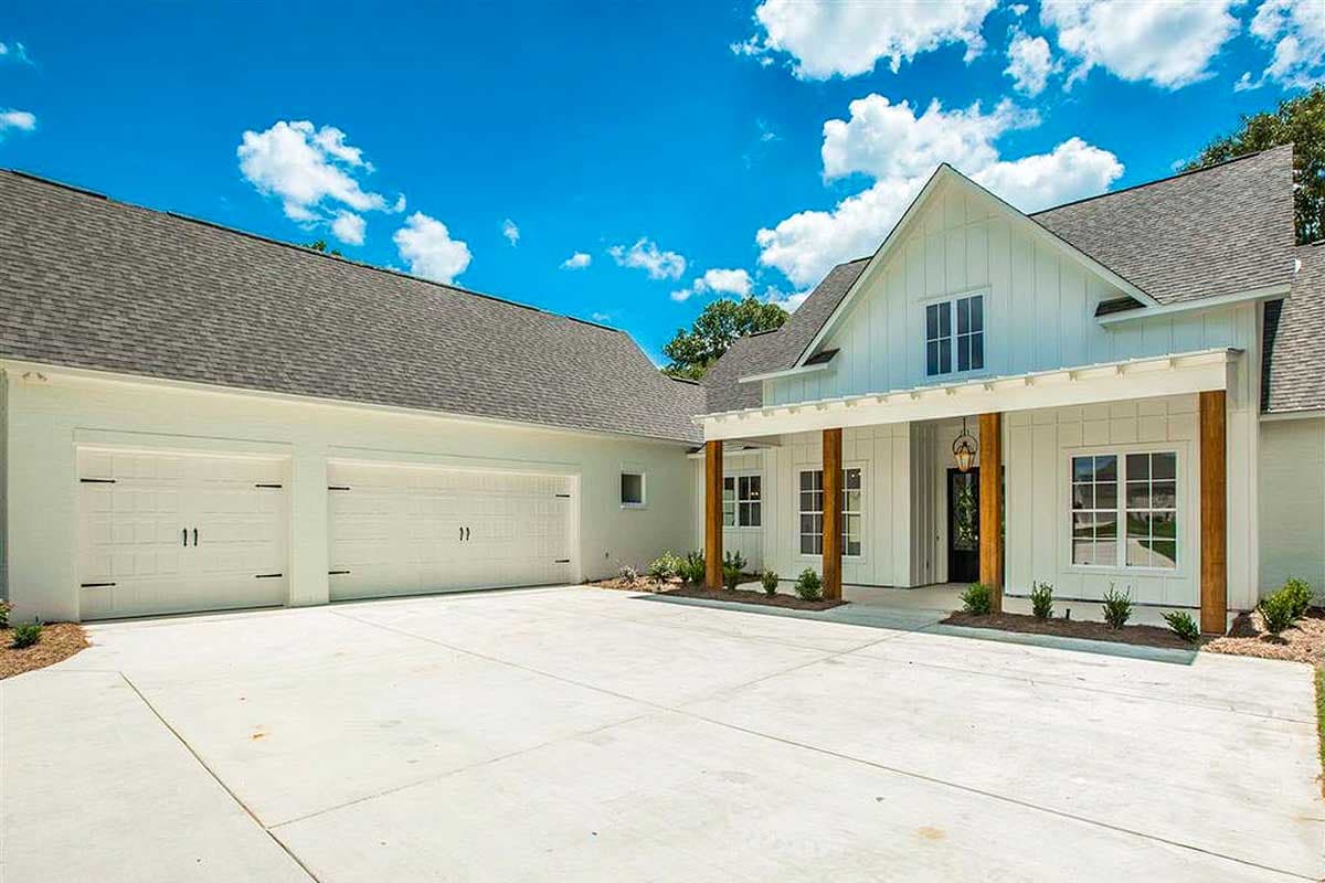Modern Farmhouse house plan exterior with a side-entry three-car garage, white board-and-batten siding, and a covered front porch with wood columns.