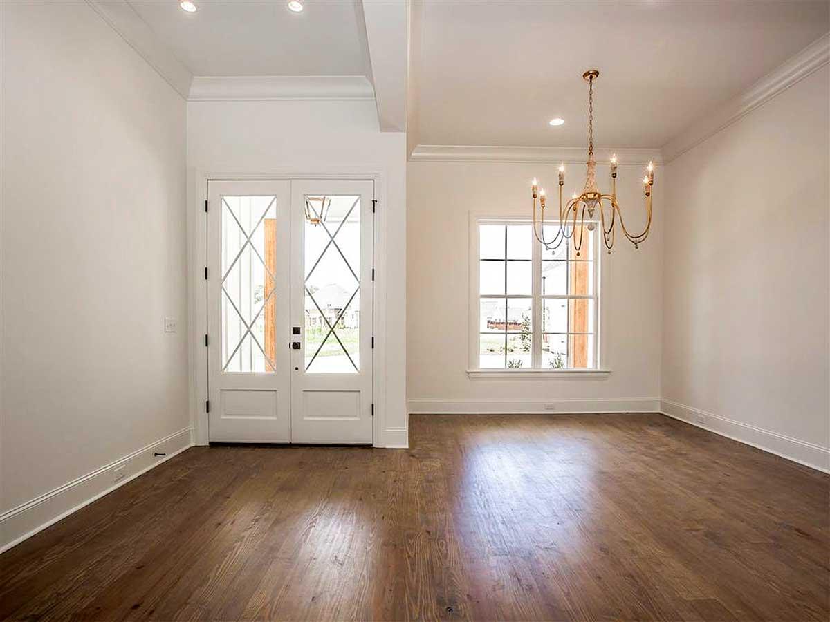 Interior view of a room with double glass doors featuring diamond pane inserts and a large window with a chandelier.
