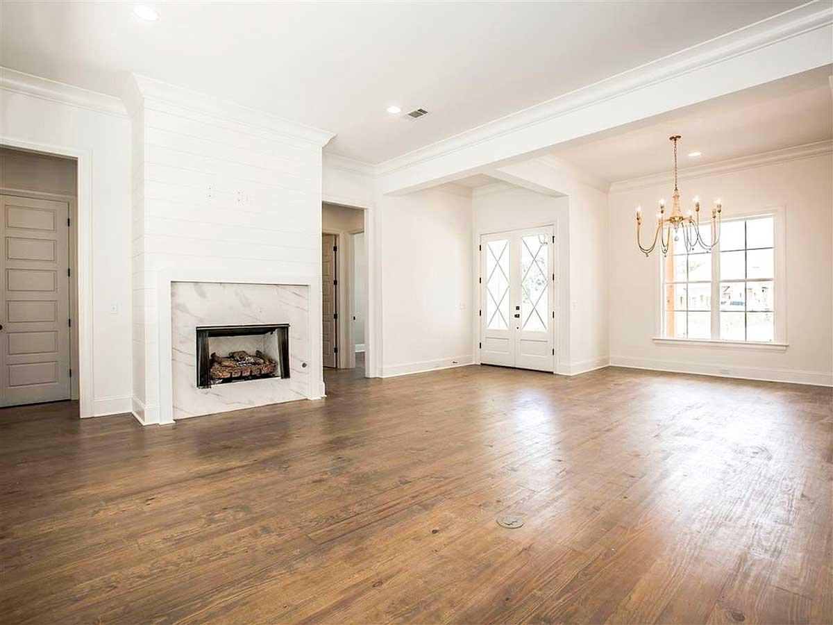 Interior view: Open living space with a shiplap fireplace, marble surround, double entry doors, and large window.