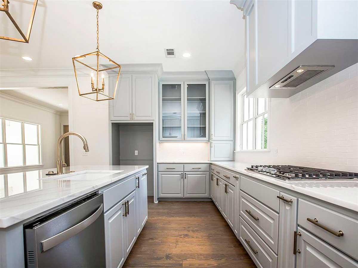 Kitchen featuring light gray cabinetry, marble countertops, gas range, stainless steel dishwasher, and a gold pendant light.
