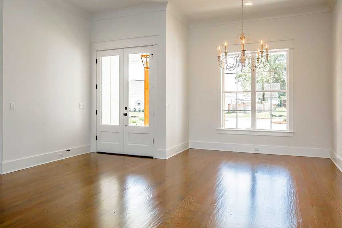 Interior view of a room with double glass doors, a large multi-pane window, and hardwood floors.