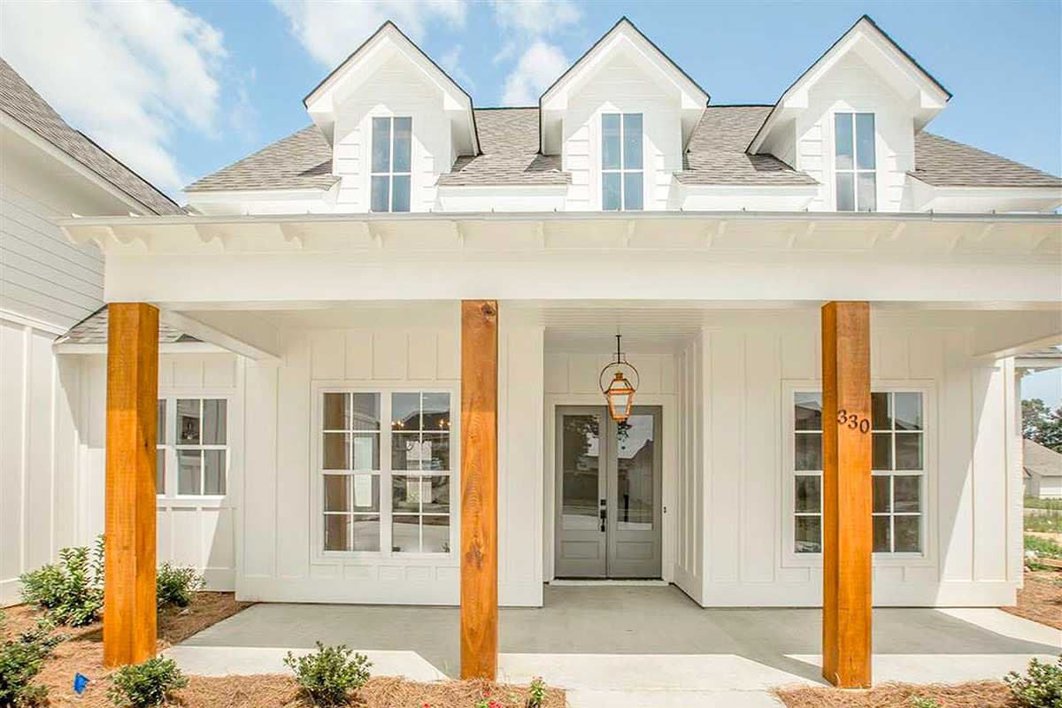 House plan exterior: Modern Farmhouse style, one story, covered porch with wood columns, multiple gables with dormer windows.