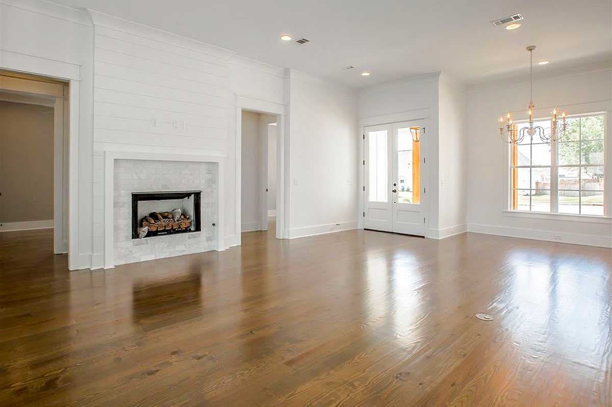 Interior view of a living area with a shiplap fireplace, marble surround, double doors, and large windows.