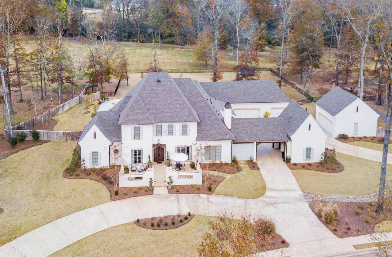 House plan exterior view of a two-story Modern Farmhouse with a porte-cochère, multiple gables, and a detached three-car garage.