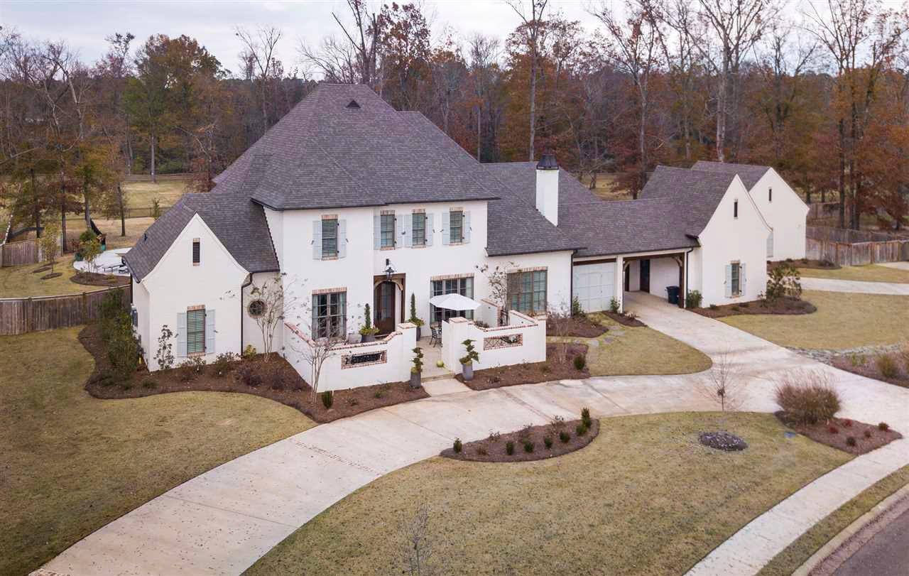 House plan exterior. Two-story home with a gabled roof, shuttered windows, and attached garage. Includes a covered entryway and patio.