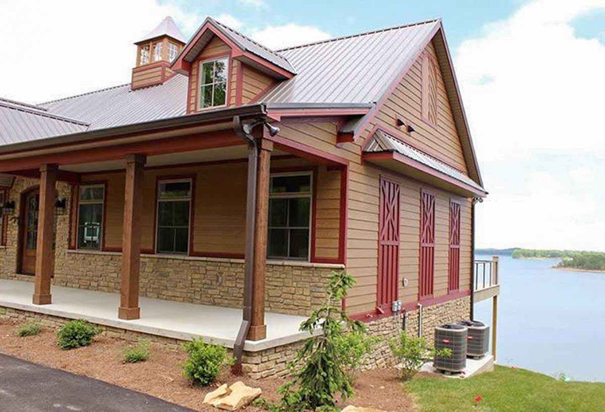 House plan exterior with stone base, covered porch, dormer, metal roof, and decorative shutters.