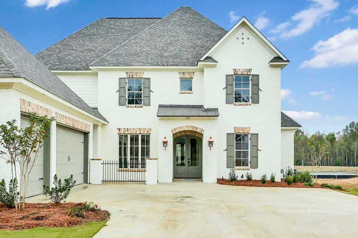 Two-story house plan exterior with white brick, arched entryway, dormer, and attached garage.