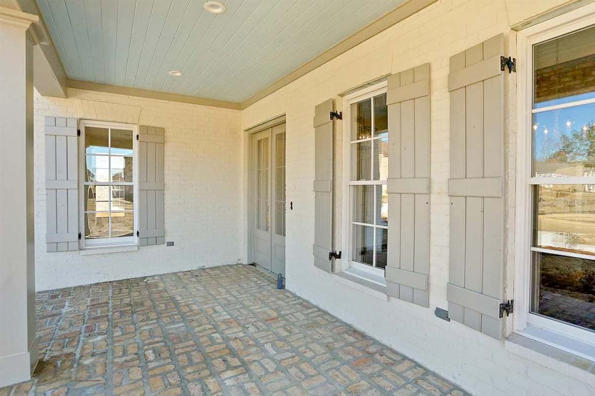 House plan exterior detail: painted brick, paneled shutters, brick paver porch floor, and paneled double doors.