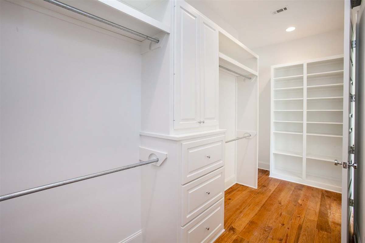 Walk-in closet with built-in white cabinets, drawers, and ample shelving. Includes clothing rods and hardwood floors.
