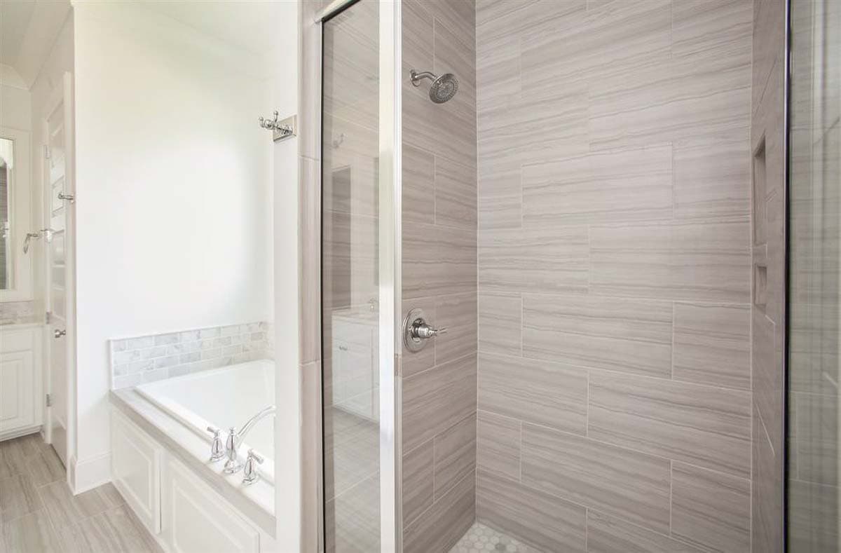 Bathroom featuring a soaker tub with marble tile surround and a glass-enclosed shower with large format tile.