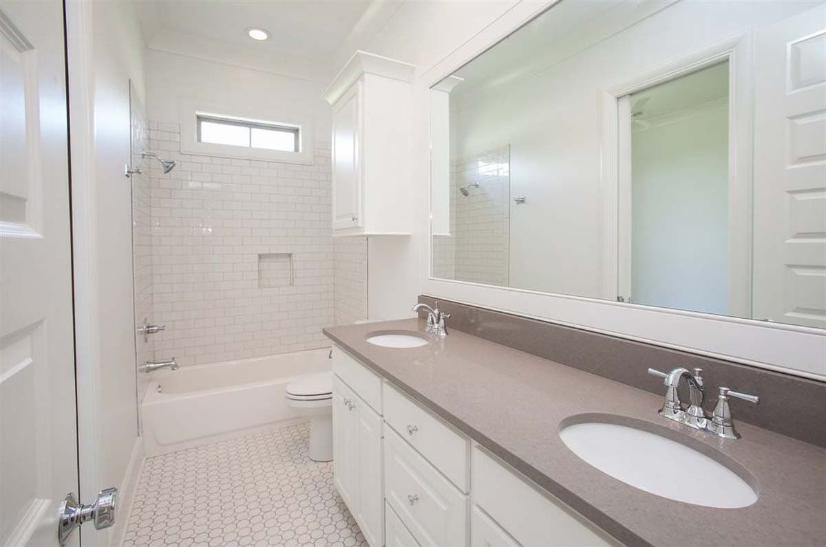 Bathroom with double vanity, white subway tile shower, tub, toilet, and hexagon tile floor.