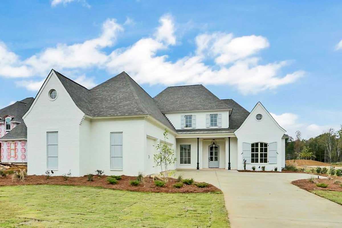 House plan exterior with white stucco facade, multiple gables, a front porch, and a side-entry garage. Two stories.