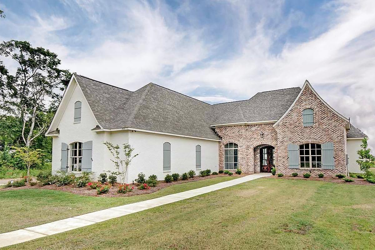 House plan exterior: One-story European-style home with brick accents, arched entry, and dormer windows.