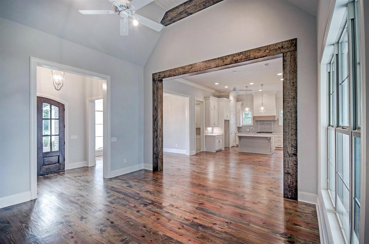 Interior view shows an entryway with arched door and open-concept kitchen with island and vaulted ceiling.