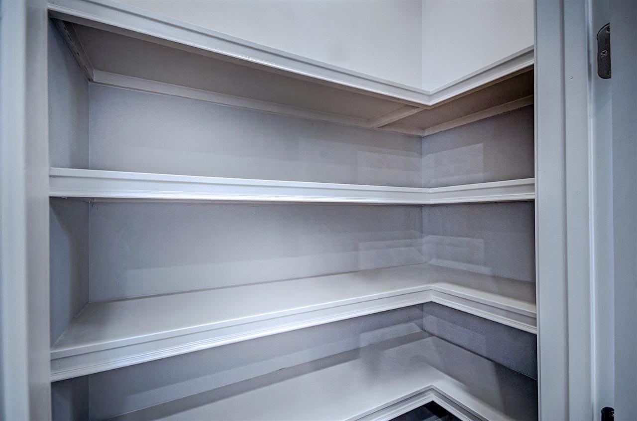Empty corner pantry with multiple shelves and decorative trim.