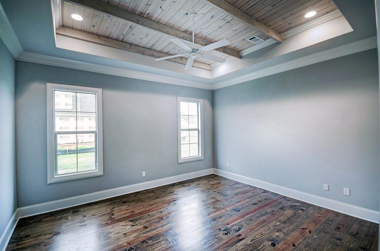 Interior view of a room with a coffered ceiling, exposed wood beams, fan, and two windows.