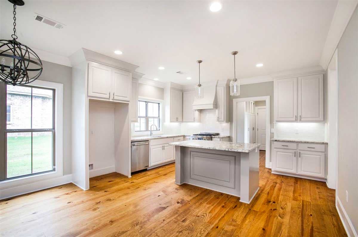 Kitchen with white cabinets, granite countertops, island with seating, stainless steel appliances, and hardwood floors.