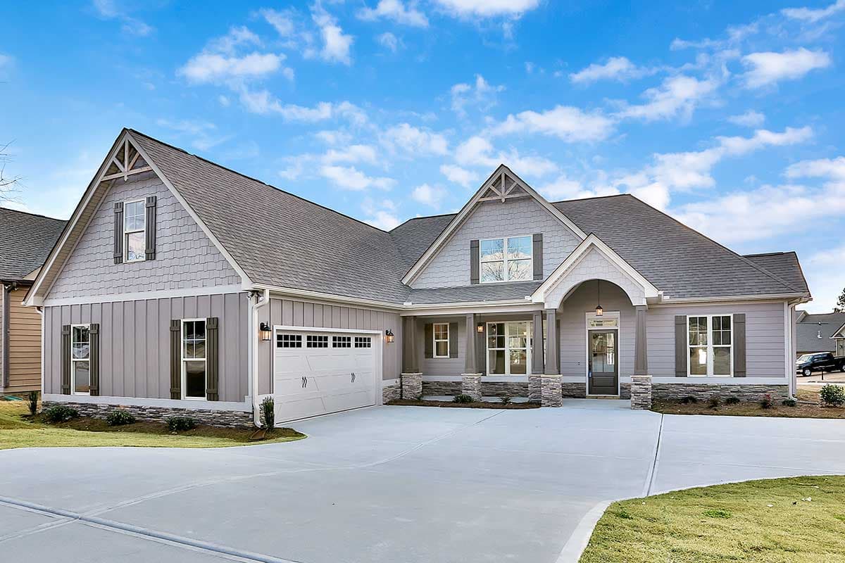 House plan exterior: two-story Modern Farmhouse with gabled dormers, arched entry porch, stone accents, and a side-entry garage.