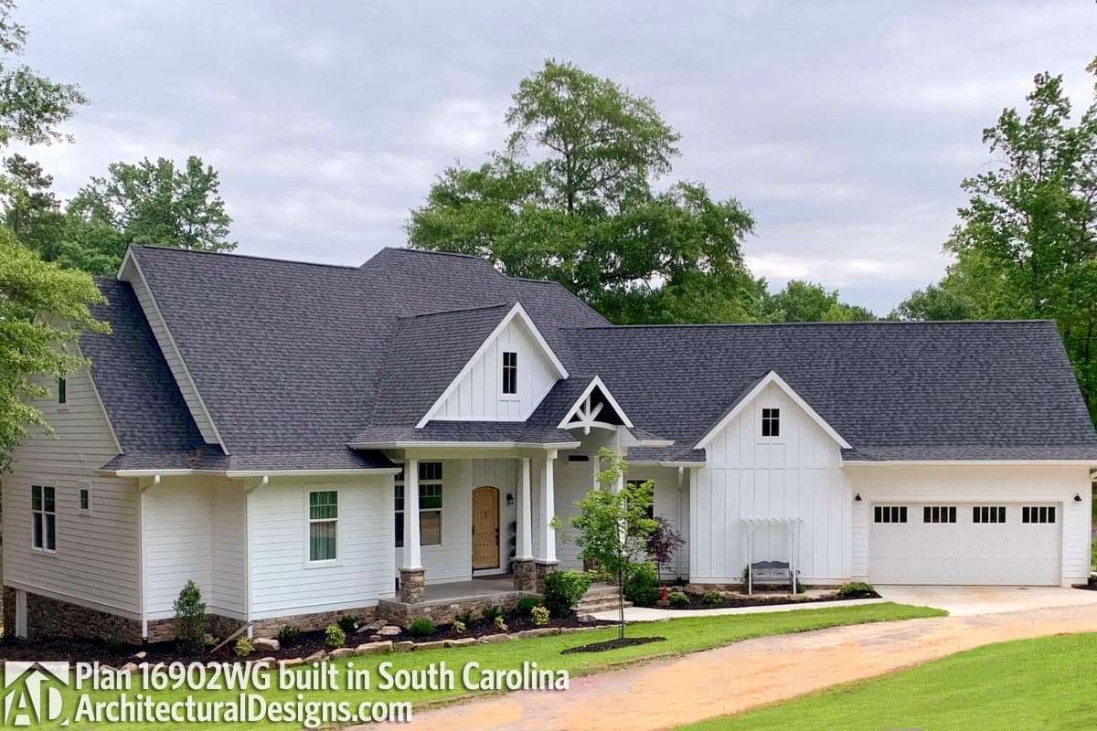 House plan exterior: Modern Farmhouse style, one story, with gables, a covered porch with stone columns, and a three-car garage.