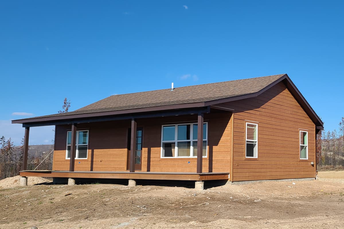 House plan exterior of a one-story Modern Farmhouse with a covered porch, wood siding, and gable rooflines.