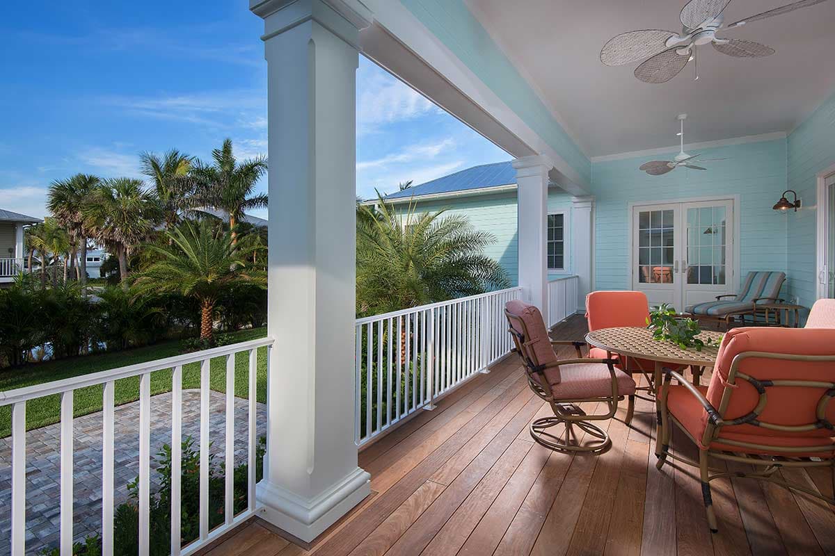 House plan exterior: Covered porch with white railings, columns, ceiling fans, and outdoor seating area.