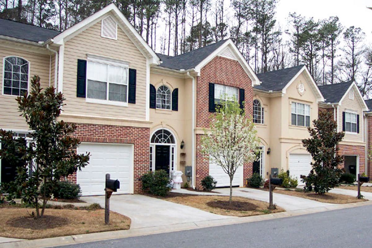Exterior house plan: two-story townhomes with brick and siding, gables, arched windows, and attached garages.