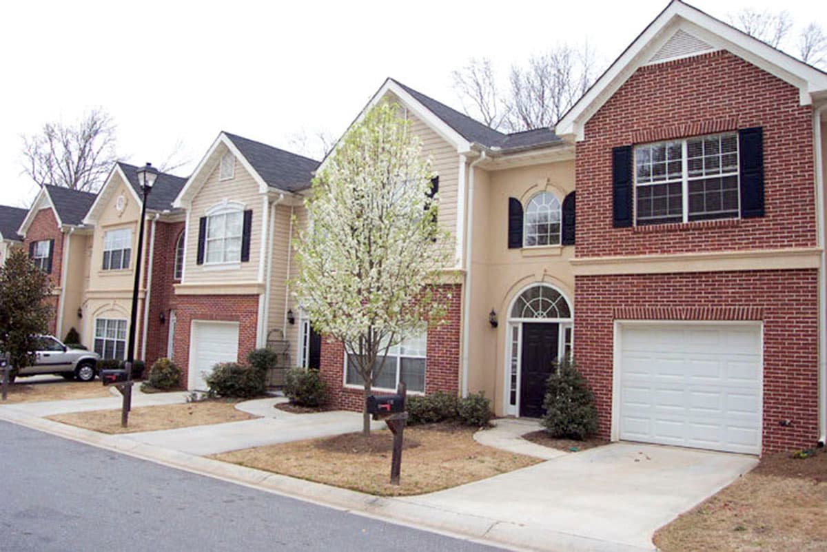 Row of two-story townhouses with brick and vinyl exteriors, arched entryways, and attached garages.