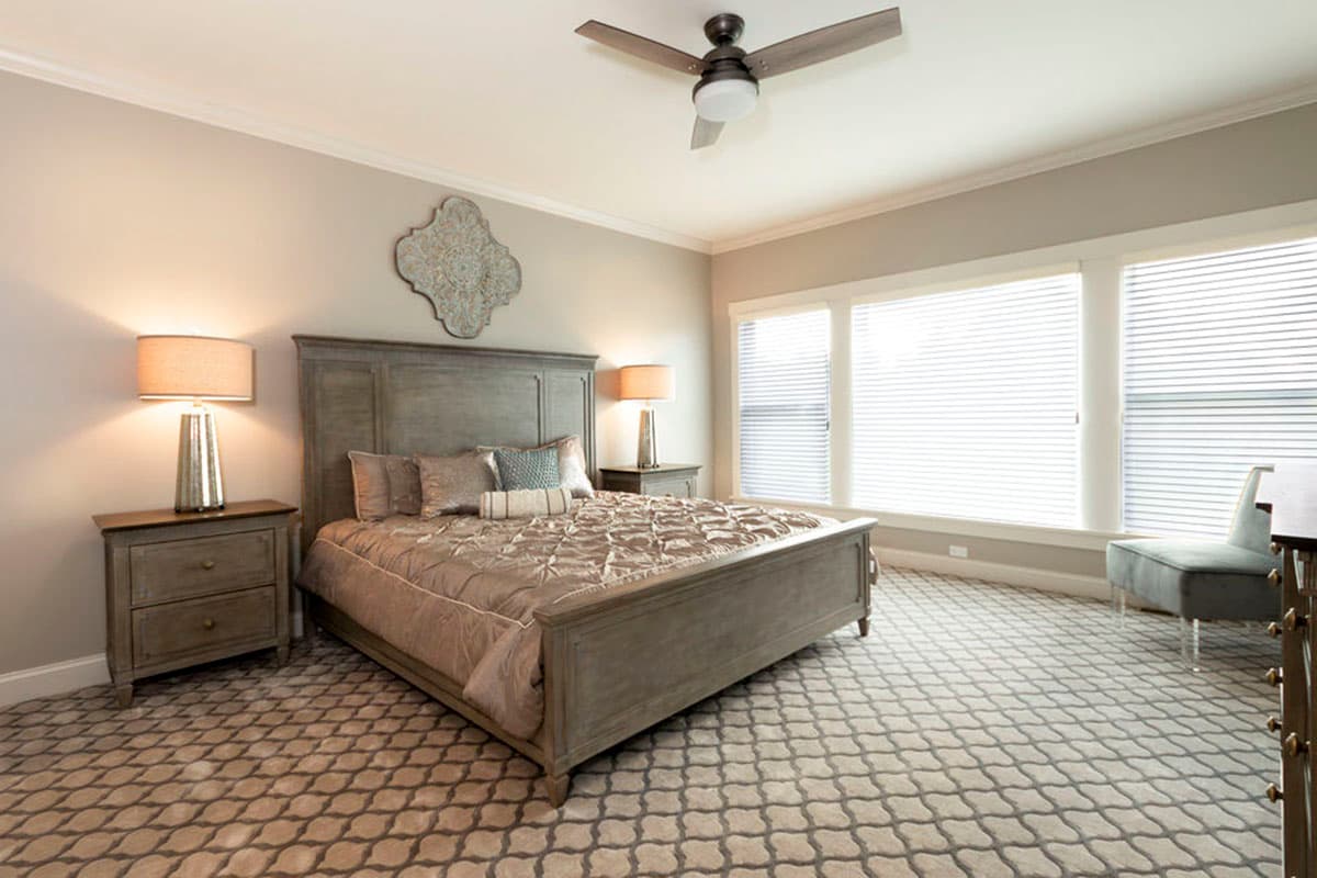 Primary bedroom with a king-size bed, upholstered headboard, two nightstands, and large triple windows.