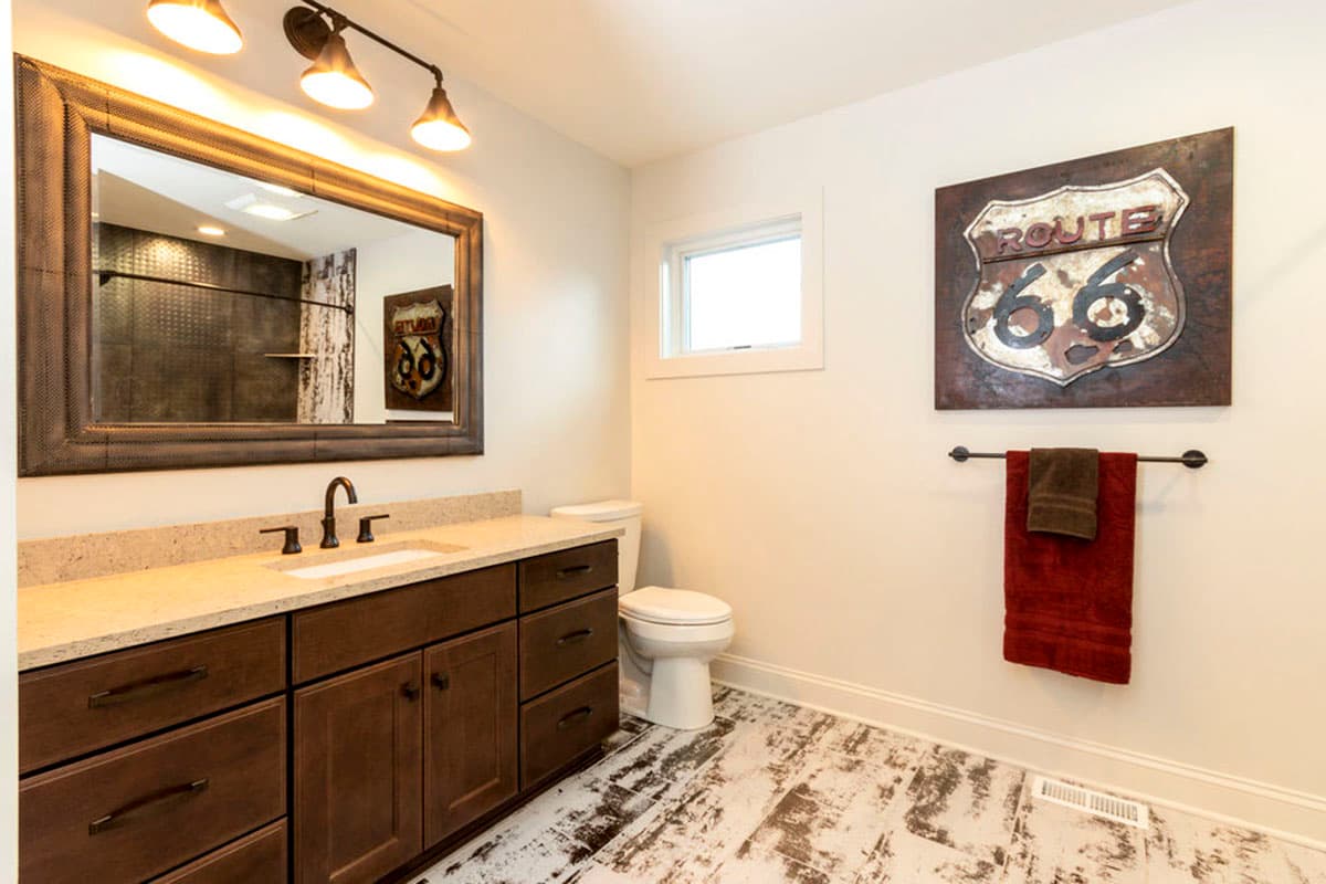 Bathroom with double vanity, granite countertop, mosaic tile accent wall reflected in mirror, and Route 66 sign.