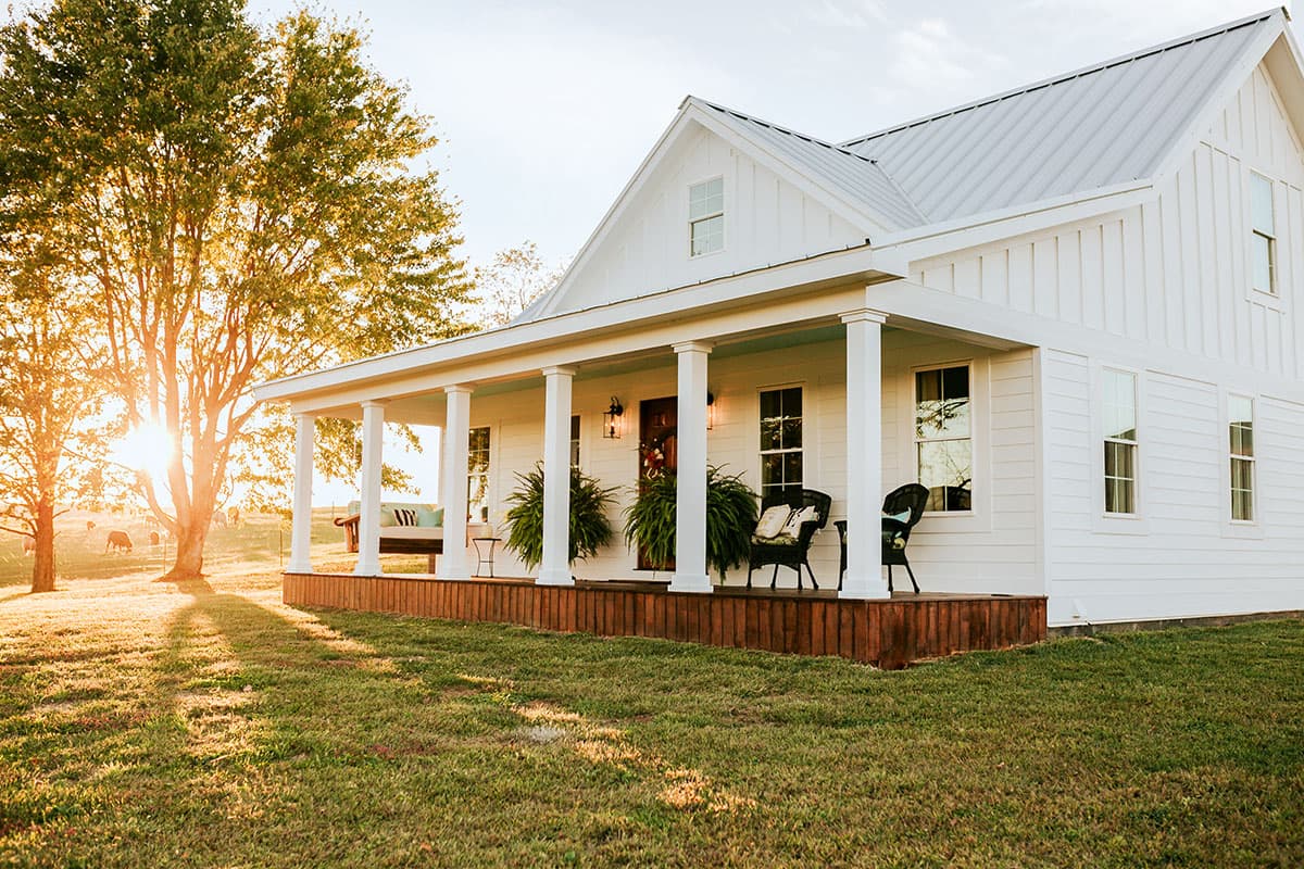 House plan exterior: White two-story Modern Farmhouse with wraparound porch, metal roof, and board and batten siding.