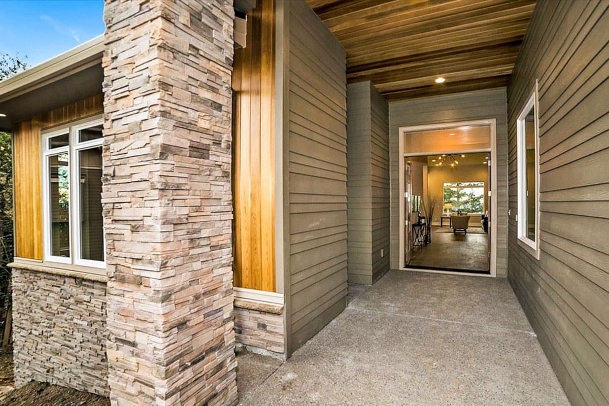 Exterior: Modern house with stacked stone column, horizontal siding, wood soffit, and wide entry.