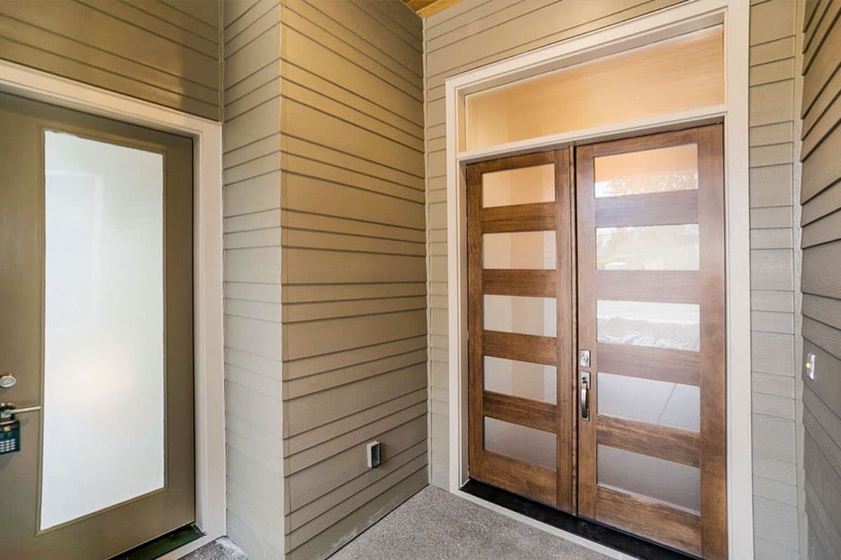 Modern house exterior with a double wood-paneled door featuring frosted glass panes and a sidelight.