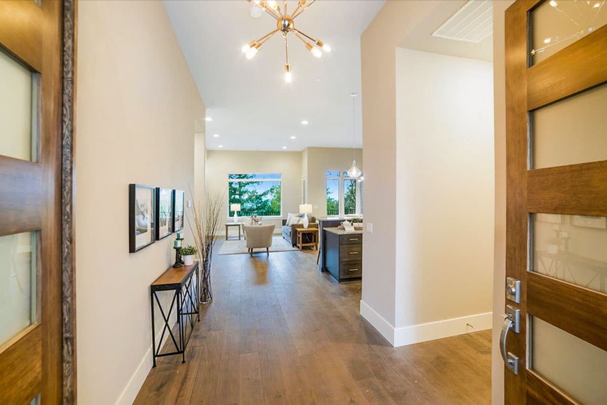 Interior view of a contemporary house plan showing an open living area with large windows and a modern chandelier.
