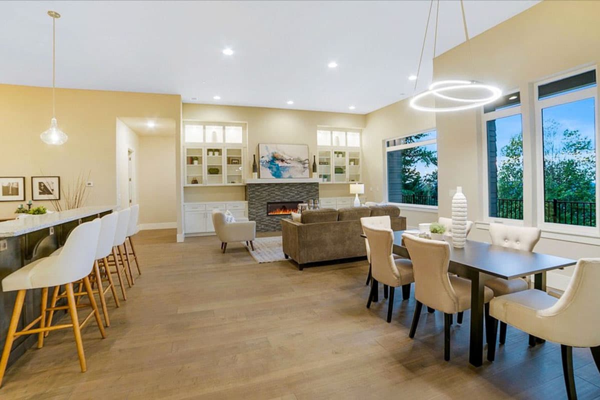 Open-concept living space with kitchen island, fireplace, dining area, and large windows.