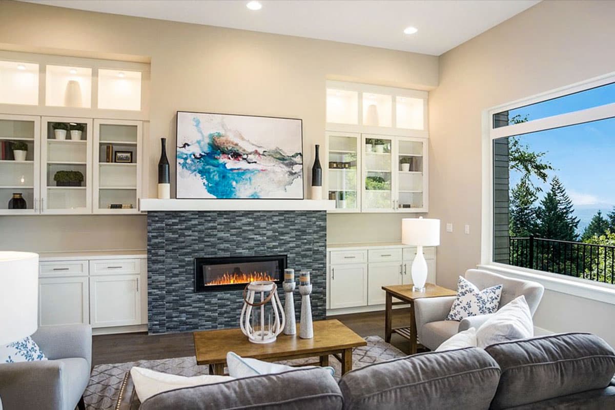 Living room with fireplace, built-in cabinetry, large window, and plush seating.