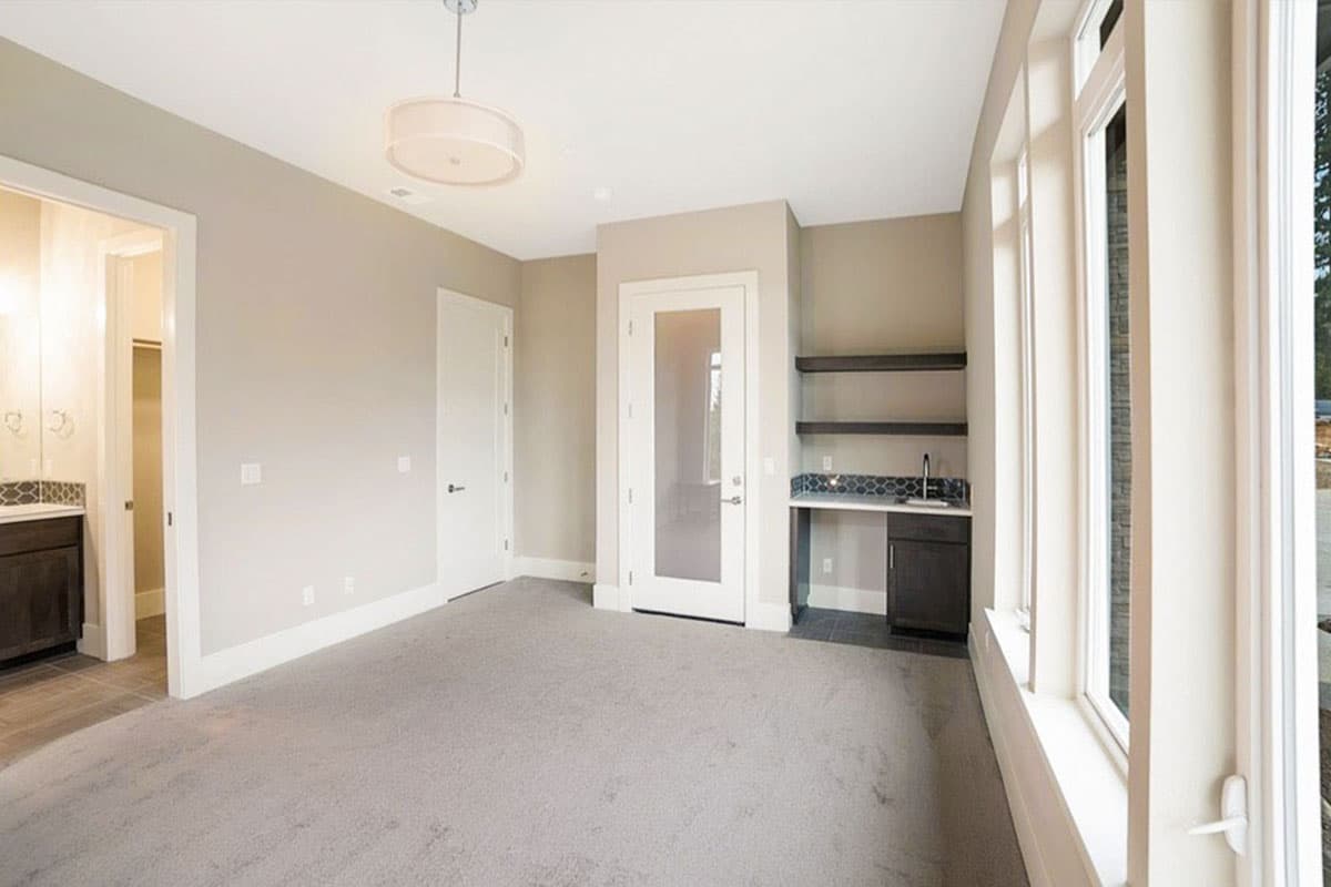 Interior view of a room with carpet, a wet bar, a glass-paned door, and large windows.