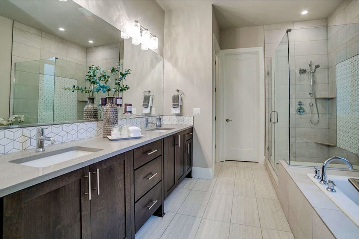 Modern bathroom with double vanity, freestanding tub, and glass-enclosed shower with tiled walls.
