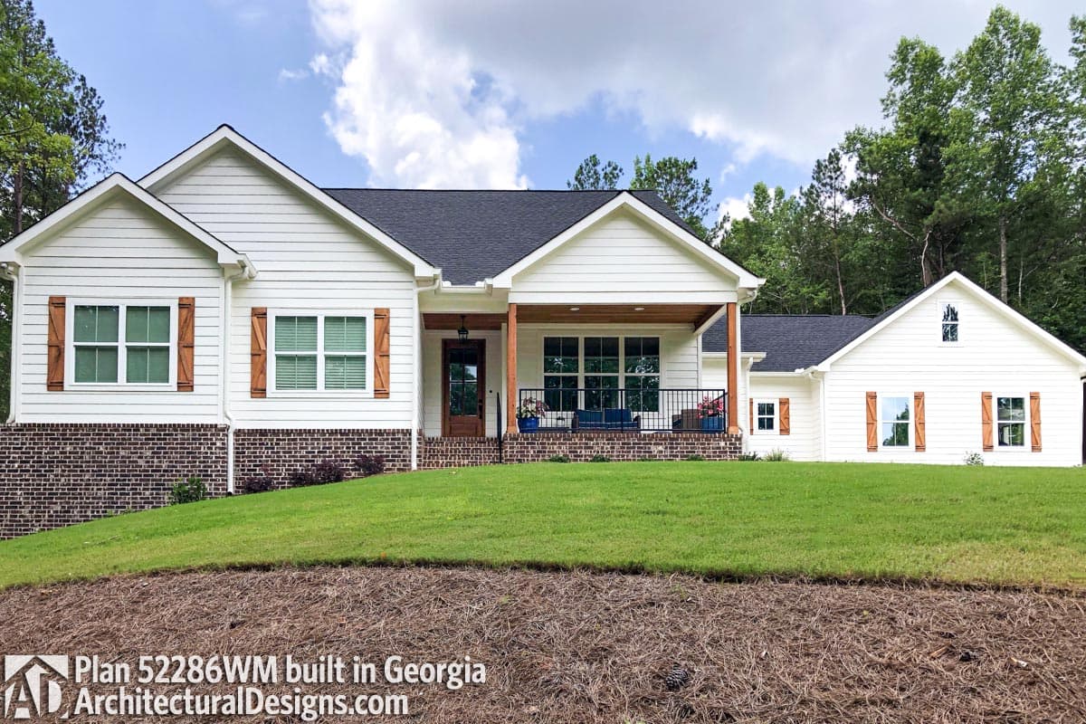 House plan exterior: White Modern Farmhouse style, one story, with a covered front porch, gable roofs, and brick foundation.