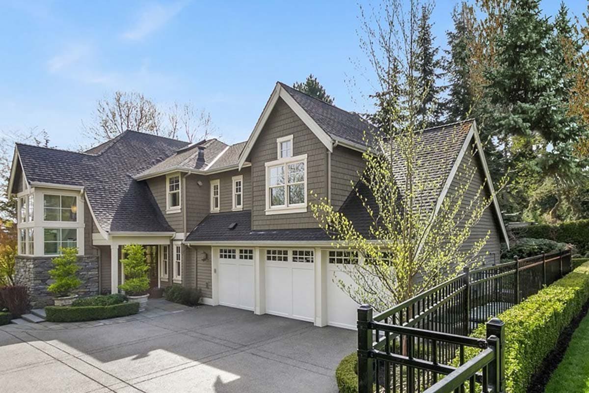 House plan exterior. Two-story Craftsman home with gabled roof, dormers, and three-car garage. Features stone facade and covered porch.